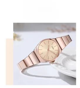 Detail view of a rose gold bamboo style metal strap and minimal watch dial on ceramic