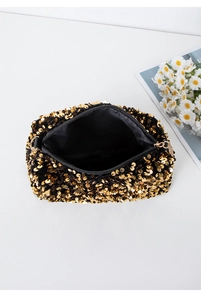 Detailed interior of a gold sequin evening clutch bag showing black lining and capacity