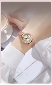 Détail d'une montre en maille milanaise or rose portée au poignet dans un décor élégant