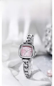 Détail d'une montre carrée argentée avec cadran en nacre rose sur fond de soie douce