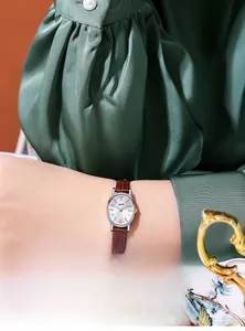 Close-up of elegant oval silver watch with brown leather strap on model wrist