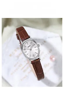 Detailed macro view of the oval silver case and dark brown leather strap of this watch