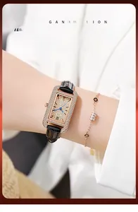 Detail of rose gold square watch with crystal dial and black leather strap on wrist