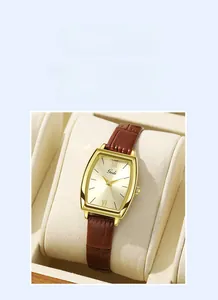 Détail macro de la montre tonneau rétro avec cadran doré et bracelet en cuir marron