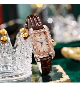 Macro shot of a rectangular crystal-encrusted watch with brown leather strap and gold dial