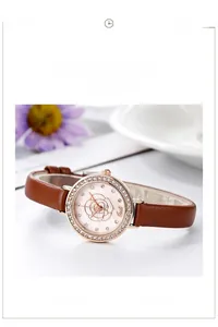 Detail of rose carved dial on ladies watch with rhinestone bezel and brown leather strap