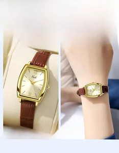 Gros plan sur une montre tonneau dorée avec bracelet en cuir brun et cadran chic