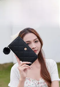 Close-up of black quilted long zipper wallet with gold rose hardware and fur pompom