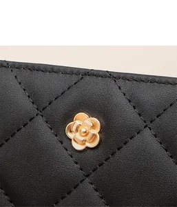 Detail of black quilted leather wallet featuring a gold flower metal ornament and stitching