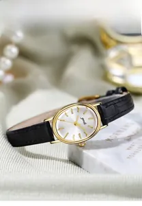 Elegant oval gold quartz watch with black leather strap on soft silk background