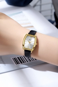 Gros plan d'une montre tonneau vintage dorée pour femme avec bracelet en cuir noir