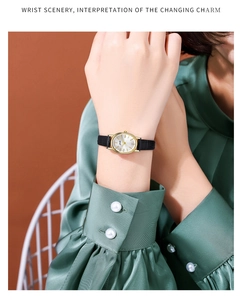 Detail of elegant oval gold quartz watch with black leather strap on a model's wrist