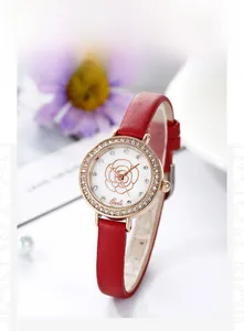 Detail of red leather strap watch with rhinestone bezel and gold camellia dial