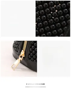 Détail d'un sac à main noir perlé artisanal avec une fermeture éclair dorée fluide