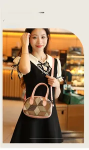 Detail view of oval crossbody bag with brown geometric patchwork and pink leather strap