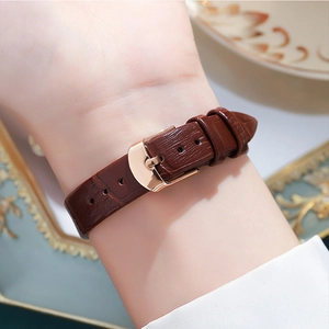 Brown leather watch strap with crocodile texture and rose gold buckle on wrist