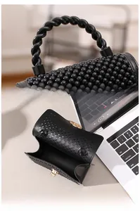 Détail du mini sac gelée noir montrant la surface perlée et le fermoir doré tournant
