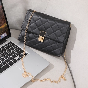 Classic black quilted leather chain handbag with gold twist lock on gray sofa background