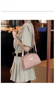 Detailed view of light pink quilted handbag with gold hardware and removable shoulder strap