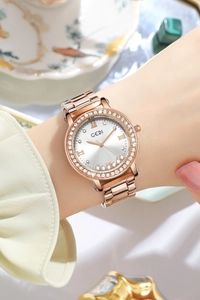 Close-up of rose gold watch featuring a rhinestone bezel and polished metal strap