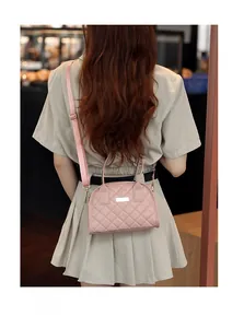 Detail view of pink quilted handbag showing weave texture and elegant metal logo plate