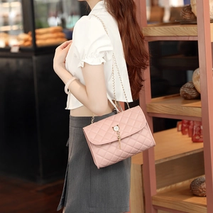 Pink quilted chain crossbody bag with cat fringe clasp shown in casual lifestyle setting