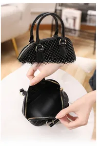 Détails d'un sac à main noir perlé avec finitions dorées et poignées rondes rigides