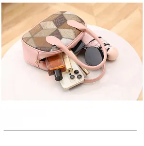 Detail view of pink handbag showing interior space with perfume, phone, and sunglasses
