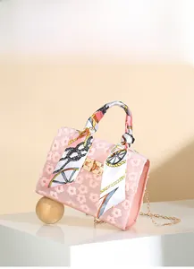 Pink floral lace crossbody bag with scarf-wrapped handle and gold chain strap detail