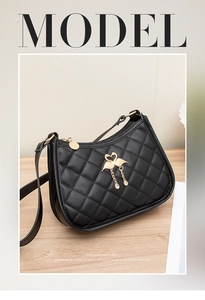 Vue détaillée du sac à bandoulière matelassé noir avec pompon flamant doré et fermeture éclair