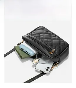 Detail view of the black quilted crossbody bag showing spacious interior and golden zippers