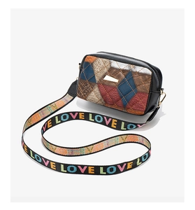 Detail of color-block quilted crossbody bag with vibrant wide jacquard strap and stitching