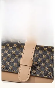 Gros plan sur l'imprimé trèfle marron et les surpiqûres d'un portefeuille cuir pour femme