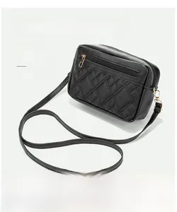 Detail of black quilted crossbody bag with golden hardware and double shoulder straps