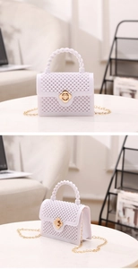 Détail du sac en perles blanches avec fermoir fleur dorée et bandoulière chaîne