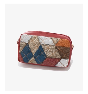 Detailed view of color-block patchwork patterns and yellow stitching on a red quilted bag