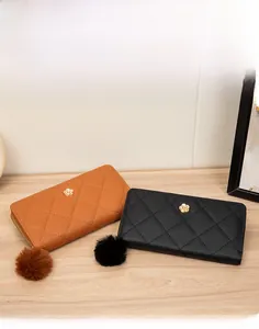 Detail of tan and black long quilted wallets with camellia metal clasp and pompom zipper