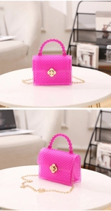 Détail du sac rose fuchsia en PVC texturé avec fermoir fleur dorée et bandoulière chaîne
