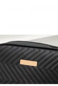 Detail of black faux leather bag with V-shaped stitching and gold metal plate
