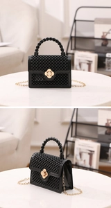 Détail du mini sac noir avec texture perlée 3D et fermoir en forme de trèfle doré élégant