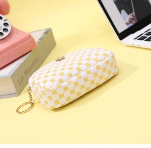 Detail of white PU leather coin purse with yellow clover pattern and gold keychain