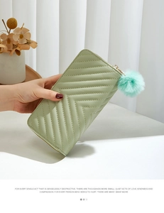 Detail of sage green quilted long wallet with double zipper and turquoise pompom charm