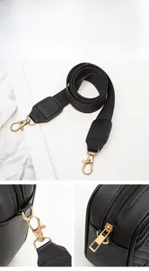 Close-up of black quilted camera bag showing gold zipper and metal strap hooks