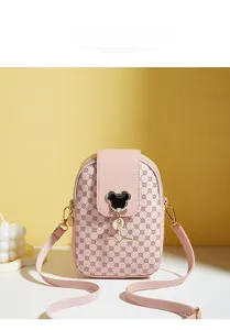 Detailed view of pink crossbody bag with circular texture and mouse-shaped metal pendant