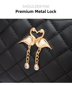 Détail d'un fermoir cygne doré avec pendentif en strass sur un sac en cuir noir matelassé