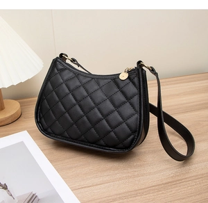 Détail d'un sac porté épaule noir matelassé avec fermeture éclair dorée sur bois