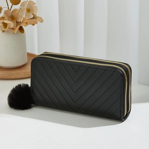 Black quilted double zipper long clutch purse for women with a plush pompom keychain