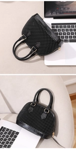 Détails d'un sac coquillage noir avec ornements de perles et finitions en cuir verni brillant