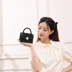 Mini sac gelée noir en PVC avec fermoir fleur dorée tenu par un mannequin élégant