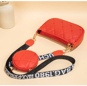 Détail du sac rouge matelassé avec petit porte-monnaie assorti et bandoulière à logo